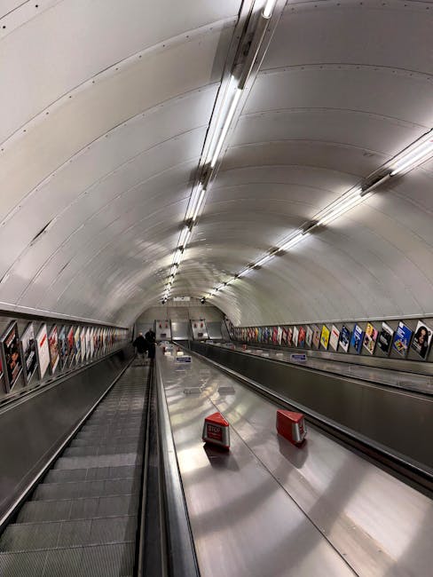 Inside Marylebone Station, the image shows a spacious railway platform with multiple train tracks extending into the distance beneath an ornate, arched metal and glass roof structure. The platform is
